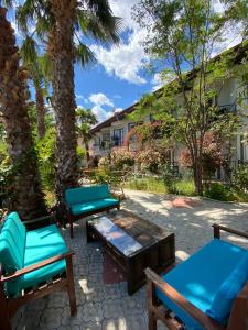 um pátio com cadeiras azuis, uma mesa e palmeiras em EON DALYAN BOUTIQIE HOTEL em Ortaca