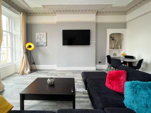 a living room with a couch and a tv on a wall at Premium 2BR Flat in the City Centre in Glasgow