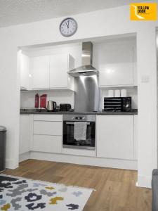 a kitchen with white cabinets and a clock on the wall at Blackie's Neuk - Ideal for Uni & West End in Dundee