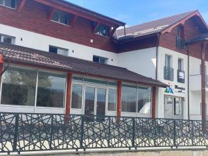 a building with a balcony with glass windows at Pensiunea Mountain Pearl in Deseşti