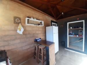 uma cozinha com frigorífico, mesa e banco em Cabana do Camelo em São Bento do Sapucaí