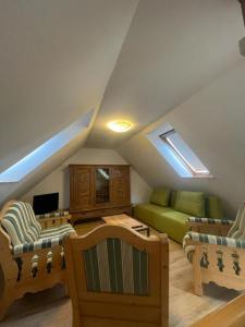 a attic living room with a green couch and chairs at Landhaus Stedtfeld in Stedtfeld