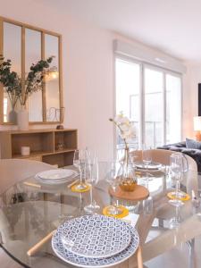un comedor con una mesa de cristal con copas de vino en Superbe appartement 2 chambres - parking gratuit en Bourg-en-Bresse