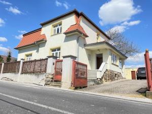 a white house with a red gate on a street at Vila Dětenice in Dětenice