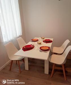 a white dining room table with red plates and chairs at La Pierre n°3 en Centre Ville in Tartas