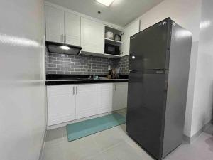 uma cozinha com armários brancos e um frigorífico preto em One Bedroom Condo Subic Bay em Morong