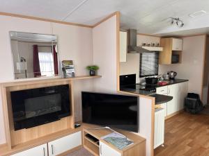 a small kitchen with a large flat screen tv at Home by the sea, Hoburne Naish Resort, sleeps 4, on site leisure complex available in Milford on Sea