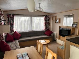 un soggiorno con divano e tavolo di Home by the sea, Hoburne Naish Resort, sleeps 4, on site leisure complex available a Milford on Sea