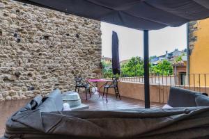 un patio con tavolo, sedie e parete in pietra di KelDomènech Apartment Bed Art a Besalú