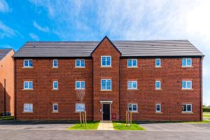 a large red brick building with a black roof at Full SKY TV Access 2BR Stylish Apartment in Hough Green