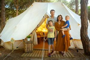 una familia parada frente a una tienda de campaña en Kampaoh Ría de Arosa Playa, en Pobra do Caramiñal