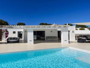 a white house with a swimming pool in front of it at Modern Villa with sea views in Sant Josep de sa Talaia