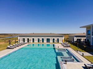 une grande piscine avec des chaises et un bâtiment dans l'établissement Vila Gale Collection Monte do Vilar, à Albernoa