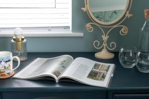 un libro abierto sobre una mesa con gafas y un espejo en Crookes House, en Weston-super-Mare