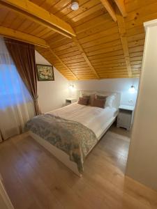 a bedroom with a large bed with a wooden ceiling at Pintea Chalet in Baia-Sprie