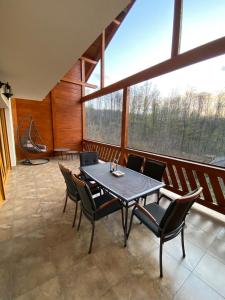 uma sala de jantar com uma mesa e cadeiras numa varanda em Pintea Chalet em Baia Sprie