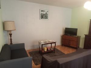salon z kanapą, telewizorem i stołem w obiekcie La Maison des Coteaux w mieście Meyrals