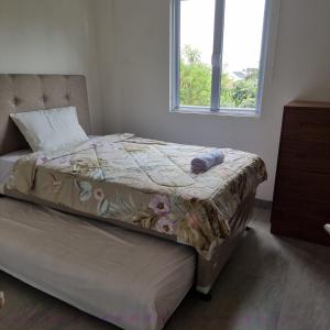 ein Bett in einem Schlafzimmer mit einem Fenster und einer Tagesdecke in der Unterkunft Rumah Tropis - Lantai 1 in Pekanbaru