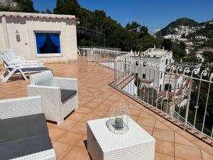een patio met witte stoelen en tafels op een balkon bij Regina di Capri - Suite vista Faraglioni in Capri