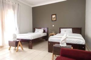 1 dormitorio con 2 camas, sofá y ventana en Kinzi Apartments Bar & Gardens, en Jinja