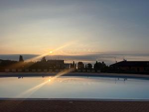 a pool with the sun setting in the background at Le Terrazze sul Lago Hotel & Residence in Padenghe sul Garda
