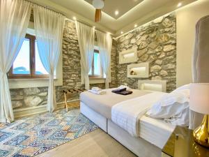 um quarto com uma cama e uma parede de pedra em Villasonboard Ermioni Rock Villa jacuzzi seaside & boat dock em Ermioni