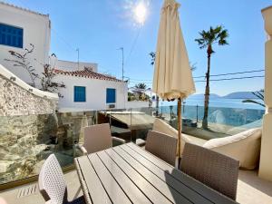 a patio with a wooden table and an umbrella at Villasonboard Ermioni Rock Villa jacuzzi seaside & boat dock in Ermioni