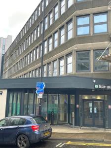 um carro azul estacionado em frente a um edifício em HNFC Stays - Modern central studio with Gym, Parking & Home Cinema em Newcastle upon Tyne