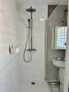 La salle de bains blanche est pourvue d'une douche et d'un lavabo. dans l'établissement COC - La Rafale, à Wissant