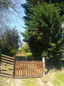 a wooden fence in front of a yard with a tree at Le Gîte insolite Gonnedouillé in Gonneville-en-Auge
