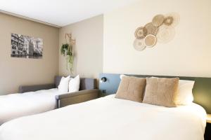 2 Betten in einem Hotelzimmer mit weißer Bettwäsche in der Unterkunft Green Park Hotel Brugge in Brügge