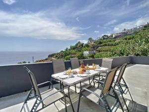 un tavolo e delle sedie su un balcone con vista sull'oceano di Villa Formosa View by Atlantic Holiday a Funchal