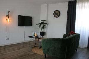 a living room with a green couch and a tv at Hotel Studio SIS in Steenbergen