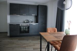 a kitchen with black cabinets and a wooden table at Hotel Studio SIS in Steenbergen