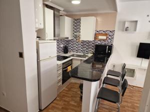a small kitchen with white appliances and black counter tops at Aventura Playa y Sol Santa Pola in Santa Pola