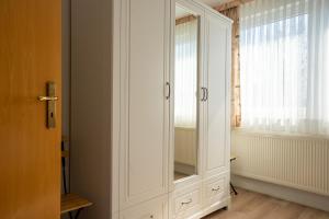 une armoire blanche dans une chambre avec fenêtre dans l'établissement Klabautermann Wohnung 6 4, à Büsum