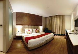 a hotel room with a large bed and a desk at Lemonwood Suites by F9 Hotels - Trivoli Garden Chhatarpur in New Delhi
