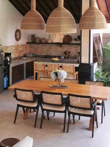 einen großen Holztisch mit Stühlen und eine Küche in der Unterkunft Villa Casa Orana in Seminyak