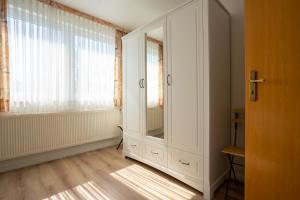 Cette chambre comprend une armoire blanche et une fenêtre. dans l'établissement Klabautermann Wohnung 6 3, à Büsum