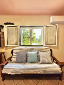 a couch with pillows in a room with a window at Jennas-Green Apartment in Cardedu