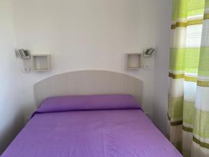 TriscinaにあるNora's Flatsの小さなベッドルーム(紫色のベッド1台、カーテン付)