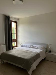 a white bedroom with a large bed and a window at Acero in Cortona