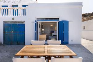 a wooden table and chairs in a room with blue doors at Ωκεανίς Κίμωλος in Kimolos