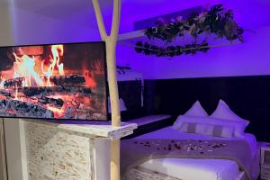 厄尔河畔帕西Vanadis, Suites d'exceptions & spa - LE BALNEO的一间卧室设有壁炉和一张桌子上的电视