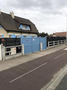 une clôture bleue sur le côté d’une route dans l'établissement Les Volets Bleus-Charmante maison entièrement équipée face à la mer pour 2 à 6 personnes, à Bernières-sur-Mer