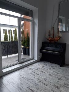 コウォブジェクにあるApartament wakacyjny Podczeleの大きな窓とピアノが備わる客室です。