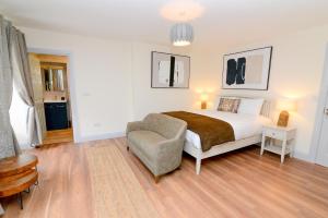 a white bedroom with a bed and a chair at Lodge at The Old Barracks in Athenry