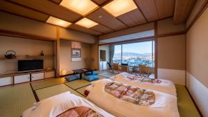 a large room with two beds and a television at onsen hotel OMOTO in Matsumoto