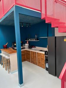 uma cozinha lego com paredes azuis e armários de madeira em Adika - The beachfront Loft em Chaloklum