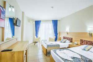 una camera d'albergo con 2 letti e una scrivania di Kleopatra Arsi Hotel a Alanya